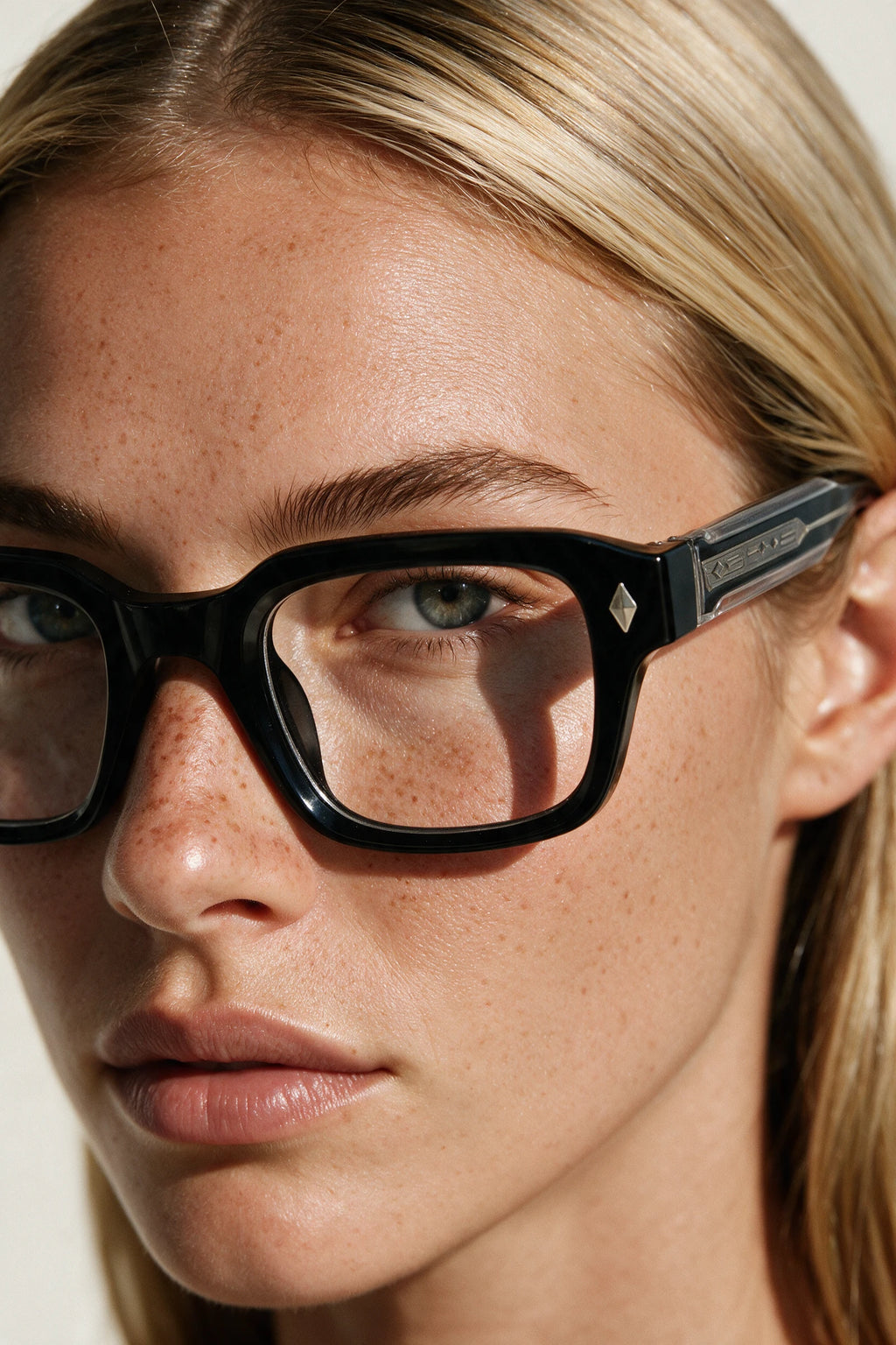 Close-up of VELA Clear glasses showing the keyhole bridge, silver diamond stud and clear band along the temple
