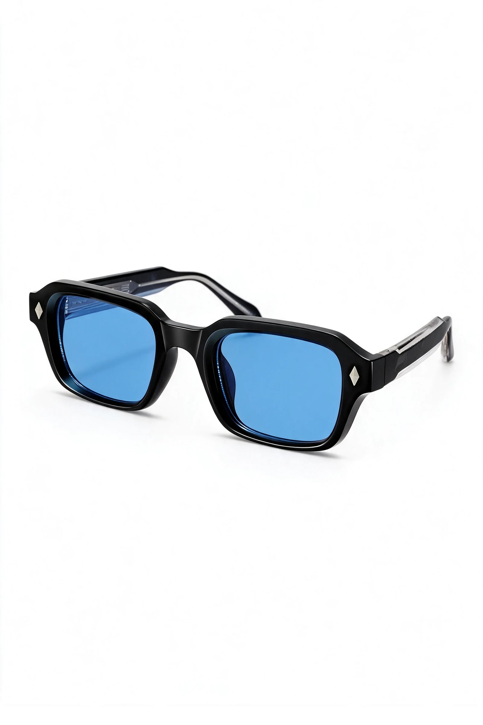 VELA Cobalt sunglasses three-quarter view showing the black-over-clear laminated temple and silver diamond stud