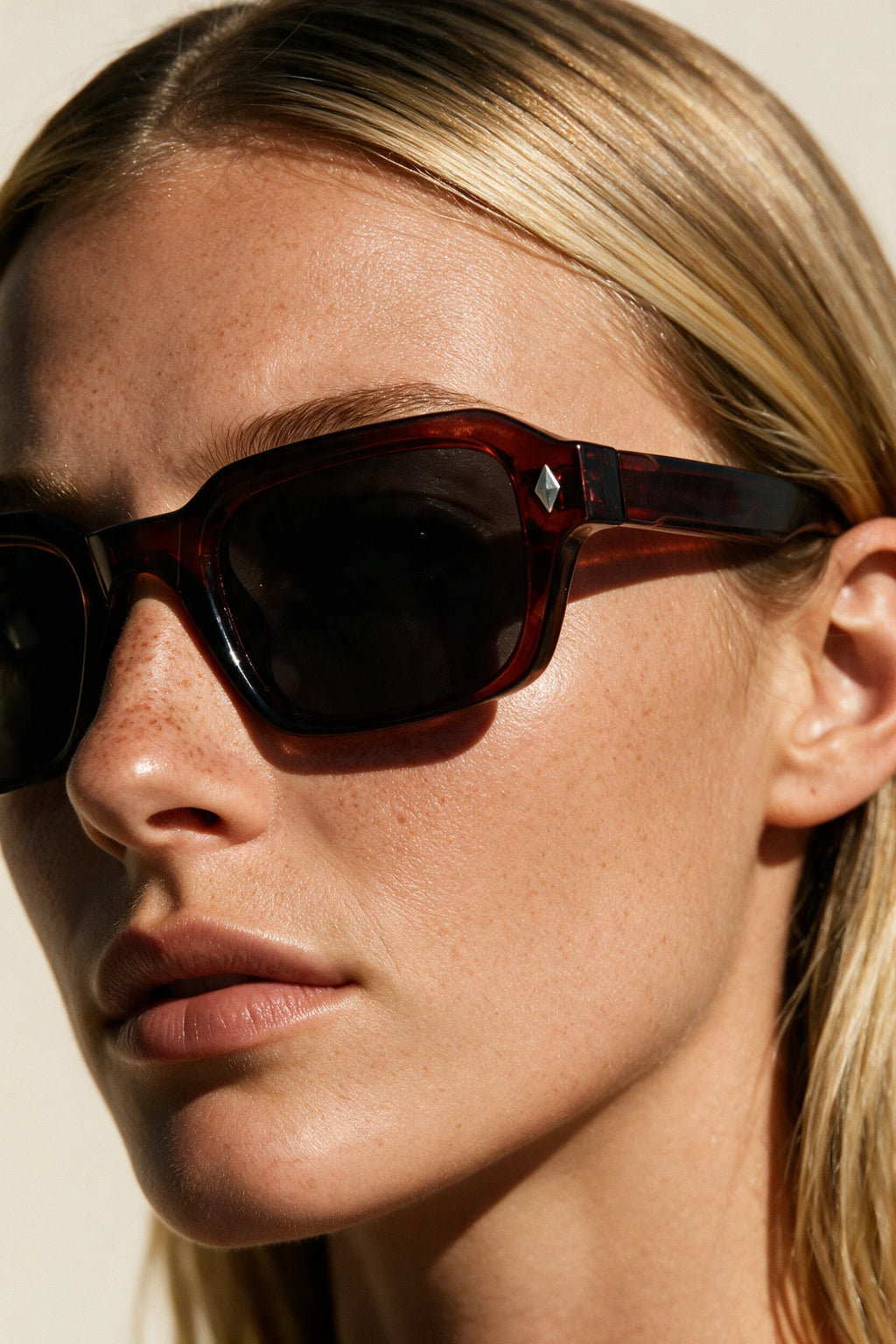 Close-up of VELA Oxblood sunglasses showing the keyhole bridge, silver diamond stud and oxblood temple