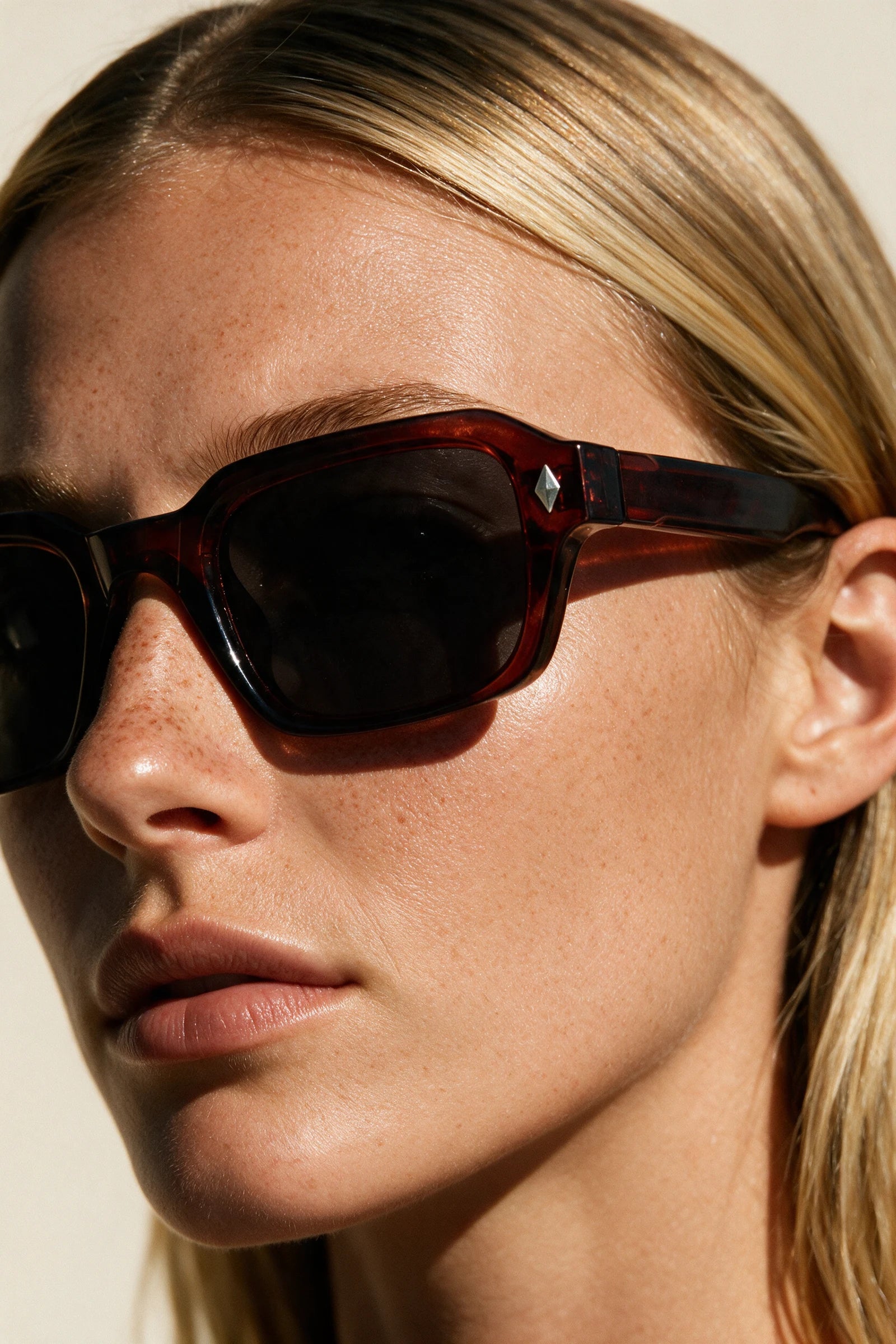 Close-up of VELA Oxblood sunglasses showing the keyhole bridge, silver diamond stud and oxblood temple