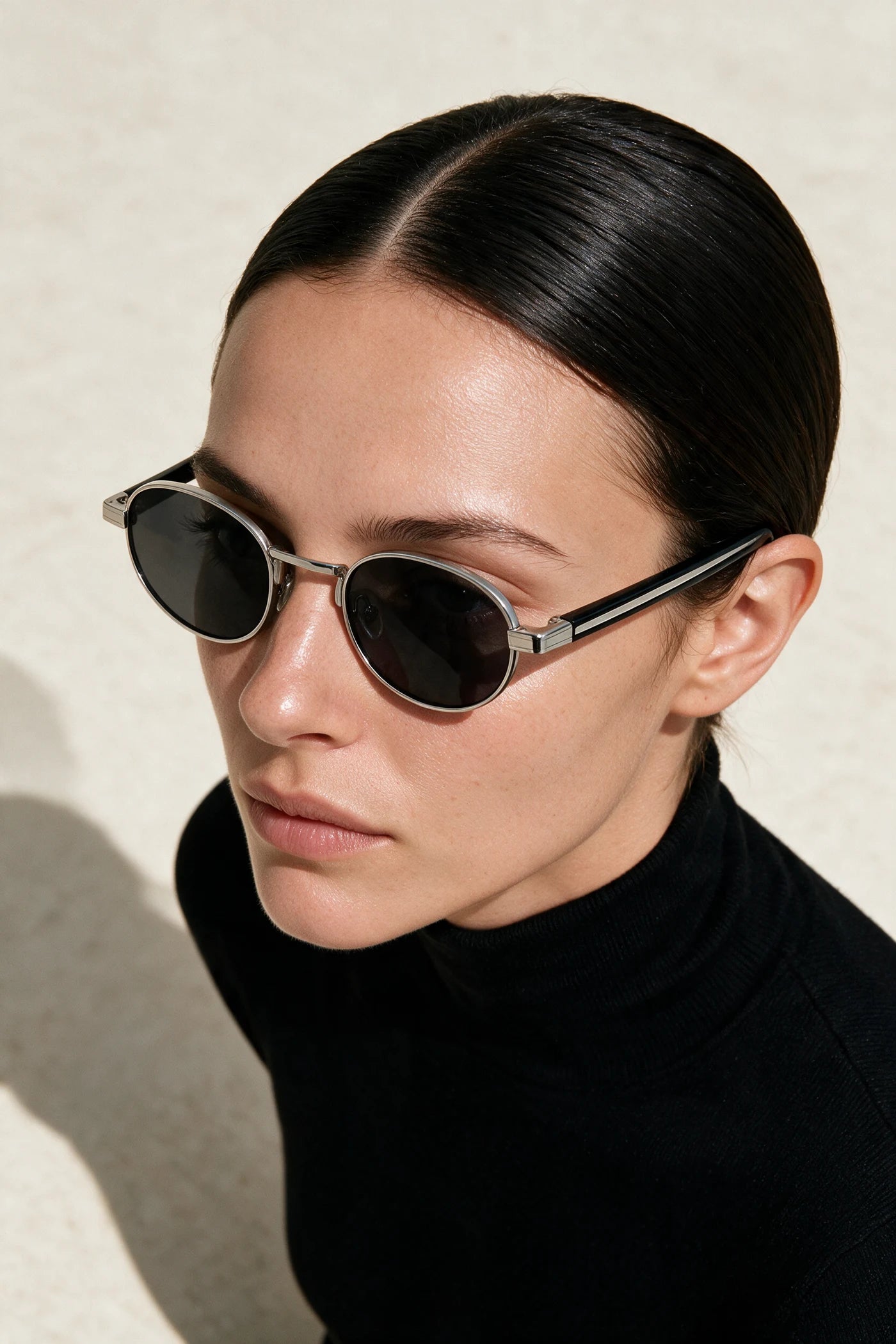 Woman wearing MARA oval sunglasses in black and silver with smoke lenses