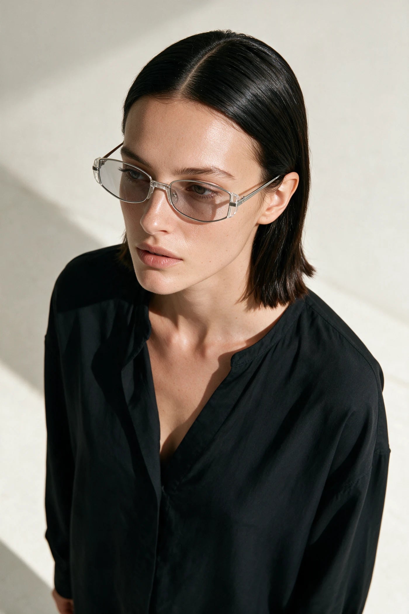 Woman wearing NEVA sunglasses in silver and clear crystal with pale grey lenses