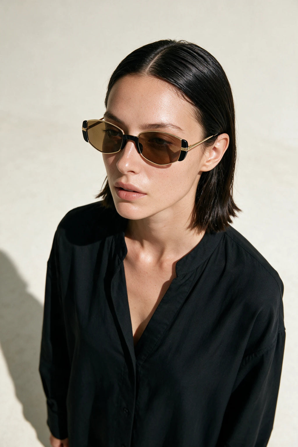 Woman wearing NEVA sunglasses in gold with tea-tinted lenses