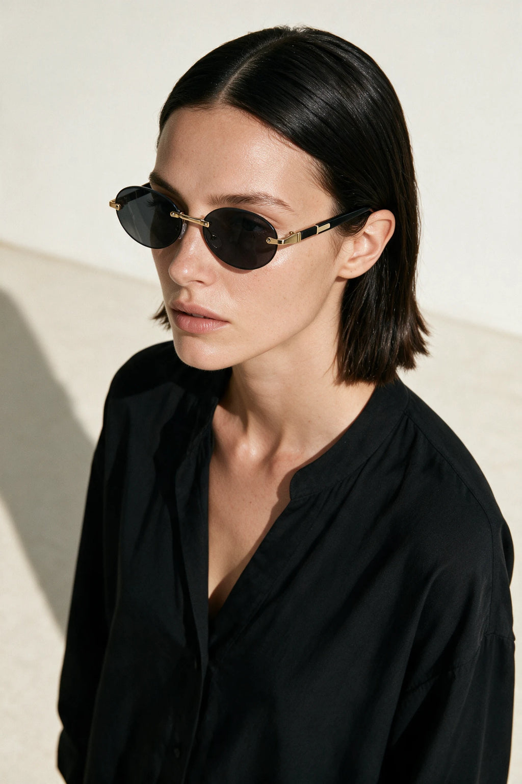 Woman wearing SERA rimless oval sunglasses with smoke black lenses