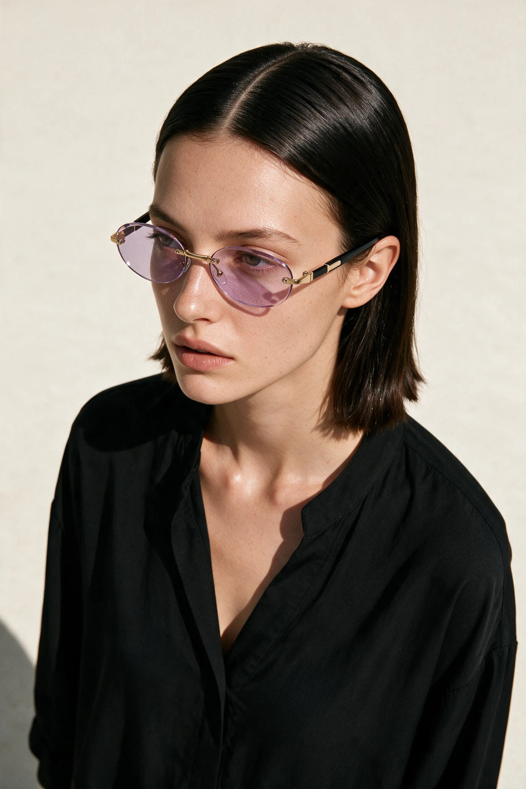 Woman wearing SERA rimless oval sunglasses with pale lilac lenses