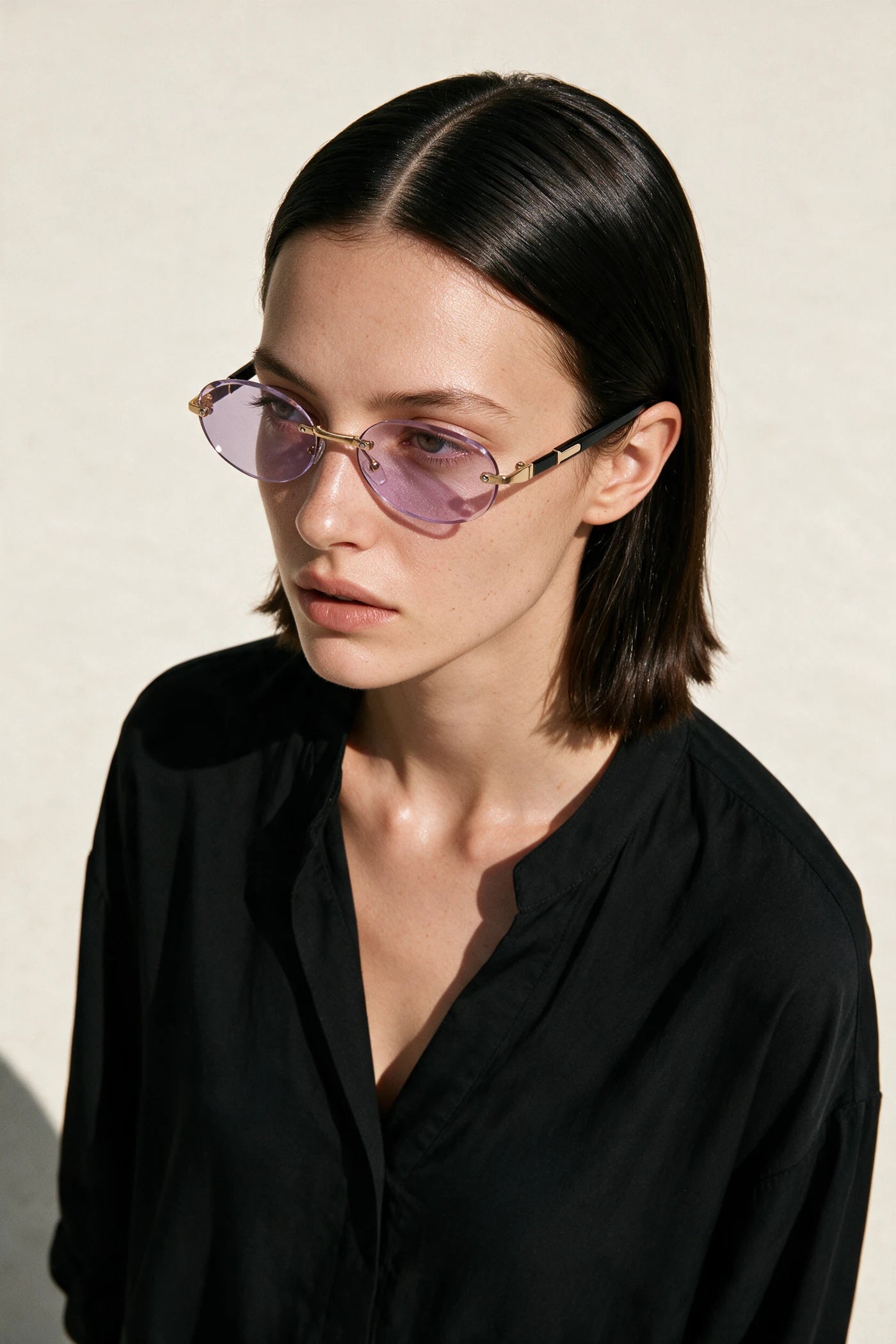 Woman wearing SERA rimless oval sunglasses with pale lilac lenses
