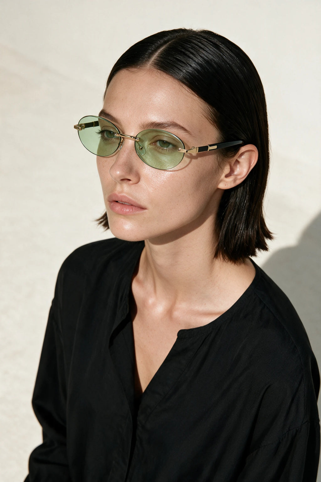 Woman wearing SERA rimless oval sunglasses with pale sage lenses