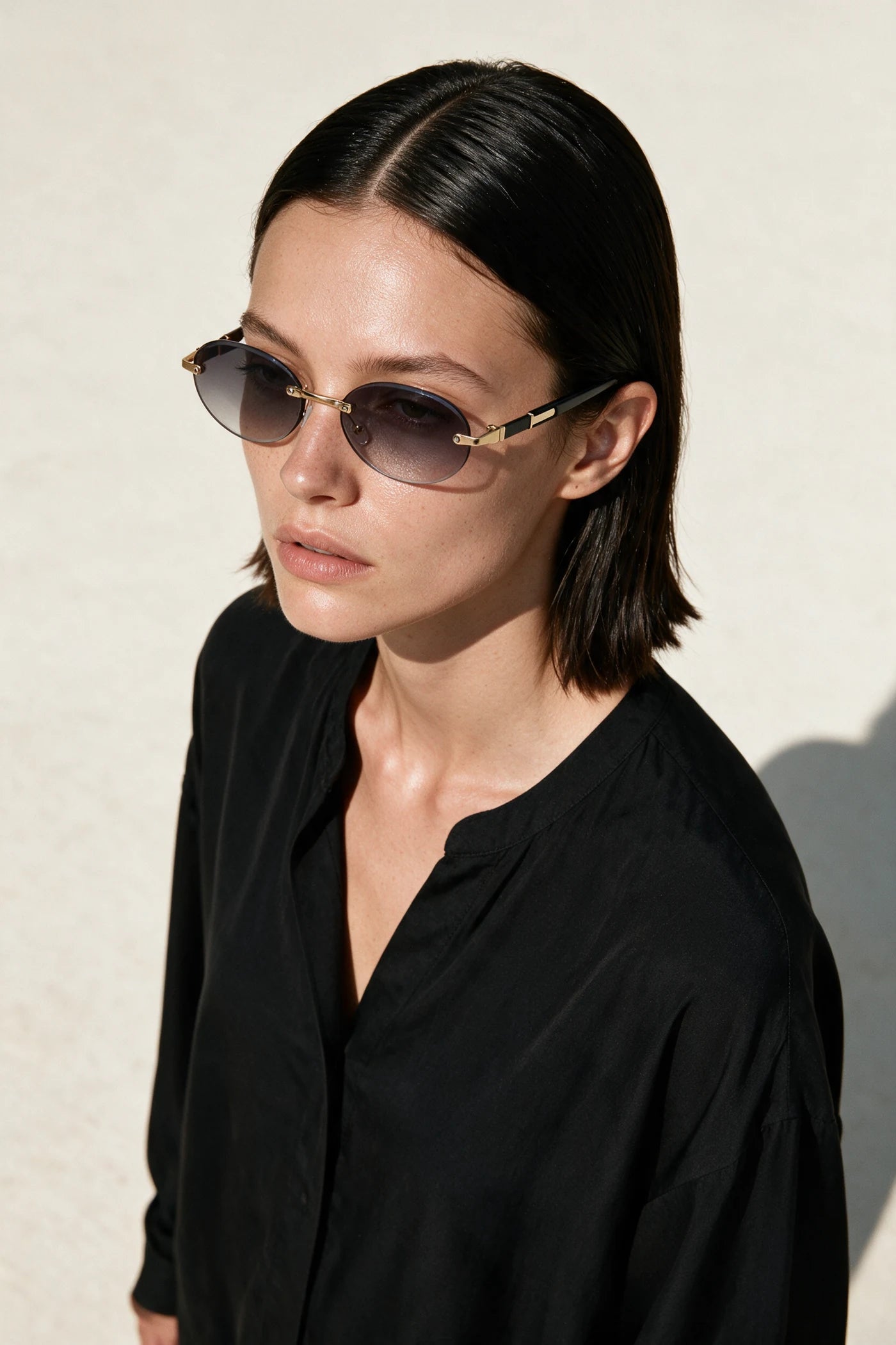 Woman wearing SERA rimless oval sunglasses with gradient smoke lenses